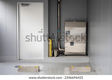 Boiler equipment. Basement business center. Wall with door. Heating technologies. Boiler equipment near wall. Boiler machine. Engineering room without anyone. Basement of office building.