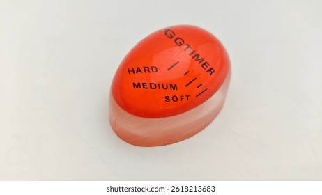 Boiling Egg Timer with Soft Medium Hard Levels. Image of a heat-sensitive egg timer used to determine egg doneness while boiling. Red kitchen accessory for perfect cooking.