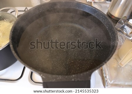 Boiling water in a pot over the fire and steam rising