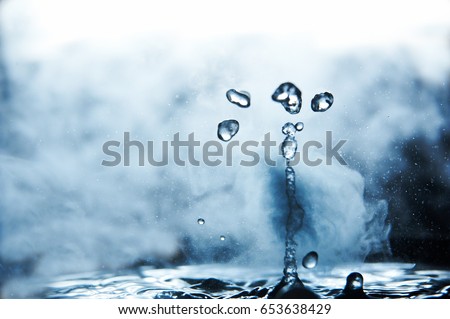 Boiling water splash with steam on black background closeup