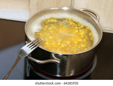 boiling yellow corn in kitchen pot on stove