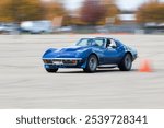 Boise, Idaho - October 31, 2021: A classic blue Corvette speeds around a race track, depicted with motion blur to emphasize the thrill of racing. The scene exudes excitement and dynamic energy.