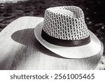 Bokeh. A fedora hat made of woven rattan on a wooden table. Photographed in black and white style.