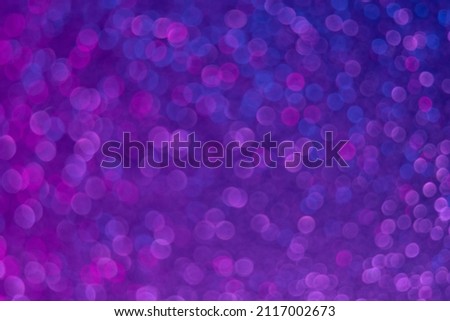 Bokeh glow. Fluorescent background. Blur firework sparks . Defocused neon purple blue color light circles pattern on dark ultraviolet abstract overlay.