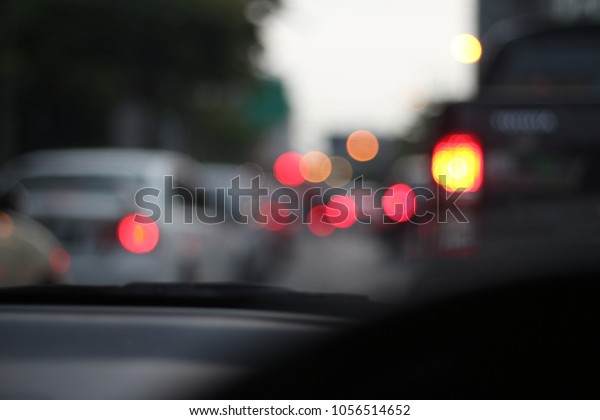 Bokeh from tail lights of the cars stuck in the\
traffic in the metropolis. View of driver from inside the car.\
Transportation problems.