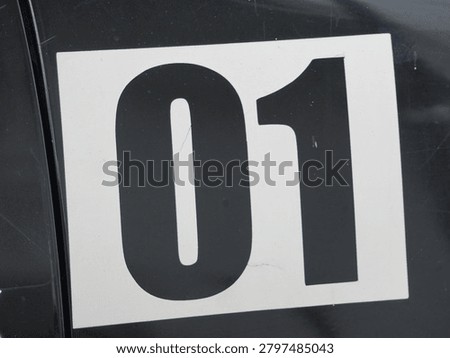 A bold black number zero one printed on a clean white square sticker featuring sharp edges and high contrast lighting