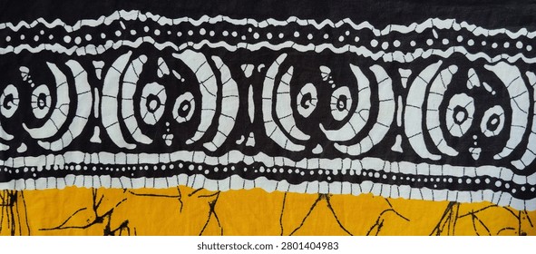 Bold black and white Batik border design with traditional motifs and crackle texture on yellow fabric background. Authentic Indonesian wax resist textile pattern for ethnic backgrounds and decorative design.  