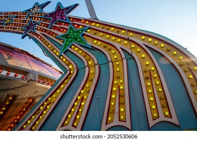 bold bright colorful light bulbs on amusement park ride shaped like shooting stars shot outdoors in natural light blue sky background with copy space