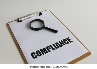 Bold Compliance Text On Paper And Magnifying Glass With Isolated White Background. Business And Financial Concept For Improvement With Implementation Of Compliance Based Audit And Quality Management.