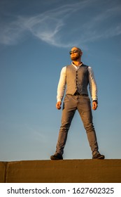 Bold Guy With A Stylish Beard And Sunglasses On A Sky Background During Sunset. Concept Of Success And Will