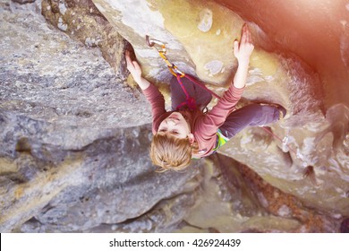 Bold kid rock climber climbs on a difficult wall.