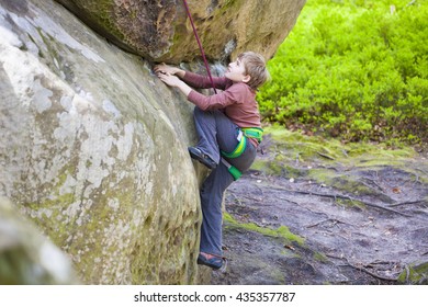 Bold Kid Rock Climber Climbs On A Difficult Wall.