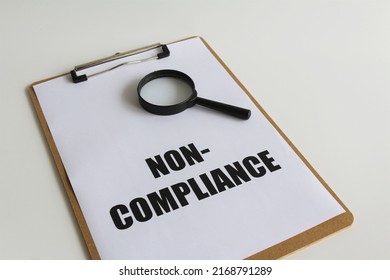 Bold non compliance text on paper and magnifying glass with isolated white background. Business and financial concept for improvement with implementation of compliance audit and quality management. - Shutterstock ID 2168791289
