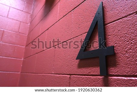 Bold number 4 on a pink cinder block wall                              