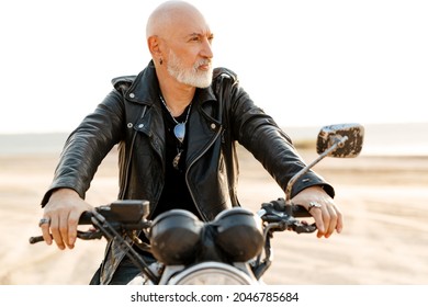 Bold Senior Man Wearing Leather Jacket Riding Motorcycle Outdoors On Summer Day