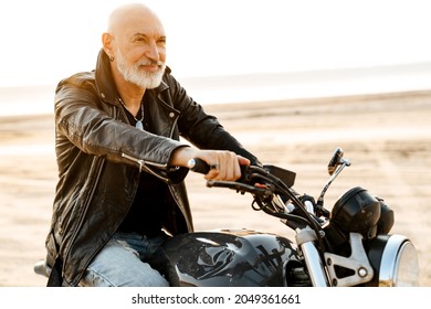 Bold Senior Man Wearing Leather Jacket Riding Motorcycle Outdoors On Summer Day