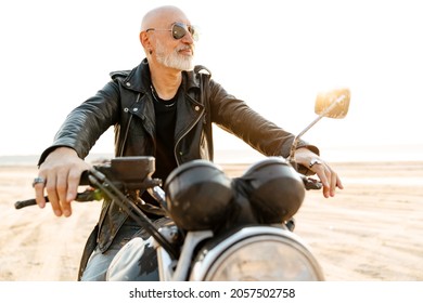 Bold Senior Man Wearing Leather Jacket Riding Motorcycle Outdoors On Summer Day