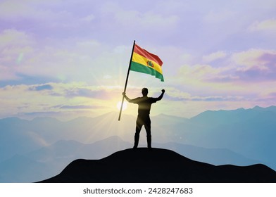 Bolivia flag being waved by a man celebrating success at the top of a mountain against sunset or sunrise. Bolivia flag for Independence Day. - Powered by Shutterstock