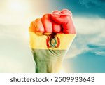 Bolivia national flag fist raise in the sky. The hand with flag raise in beautiful soft sky. Bolivia national flag for independence day.