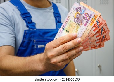 Bolivian Worker Showing Money. Bundle Of Banknotes, Salaries Of Professionals And Blue Collar Workers