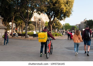 Bologna, Italy - 13 April 2019: Young Boy Glovo Rider Making Delivery On His Bike Working In The So Called Gig Economy Barcelona Main Square