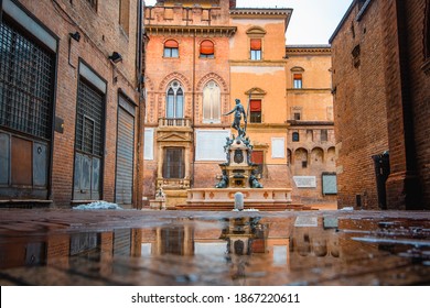 Bologna in the morning, looking Neptune statue in main square with sunlight and reflection in a puddle on the street