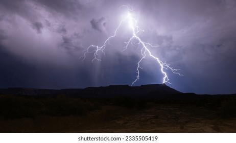 A bolt of lightning splits into several branches as it flashes in the stormy night sky above Gooseberry Mesa in Southern Utah during a summer Monsoon storm. - Powered by Shutterstock