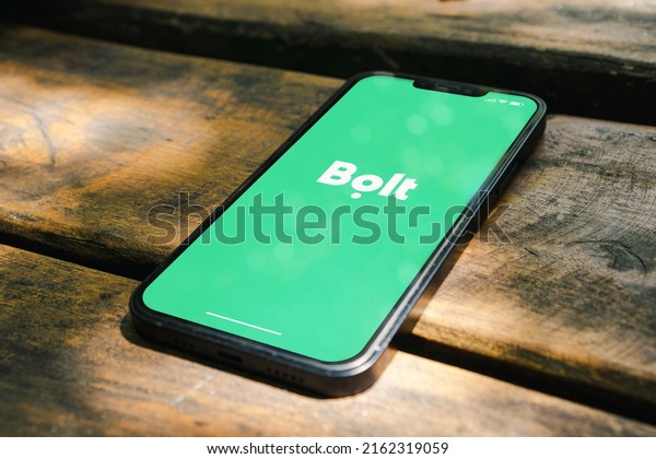 Bolt mobility company streaming app on\
the smartphone screen on the rustic wooden table in the park. Top\
view. Rio de Janeiro, RJ, Brazil. May\
2022.