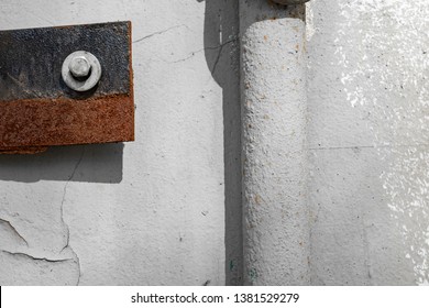 A bolt with a washer attaches a plate with corrosion to the wall