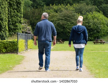 Bolton, Lancashire/UK - June 16th 2019: Caucasian Middle Age Couple Walking Apart On Path In Park