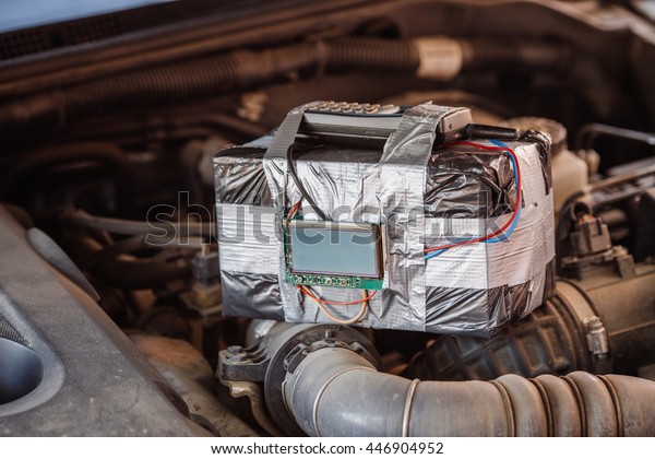 bomb with radio\
control and digital countdown timer on a car engine. terrorism and\
dangerous life concept