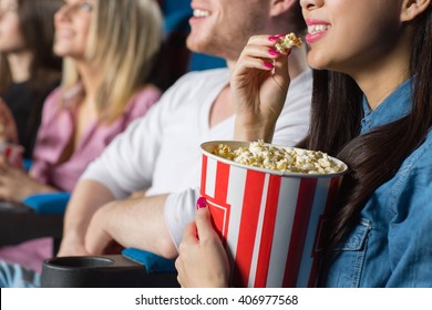 Bon appetit! Closeup shot of a young woman feeding her cheerful laughing man with popcorn at the movie theater - Shutterstock ID 406977568