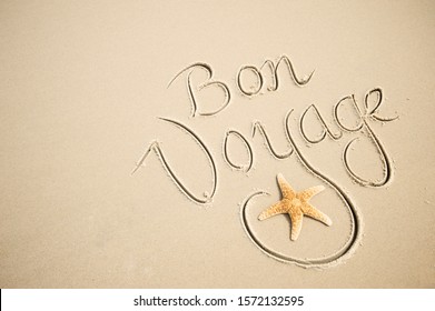 Bon Voyage (English translation: Have a Good Trip) message handwritten with a calligraphy script on a smooth sand beach with a starfish flourish - Powered by Shutterstock