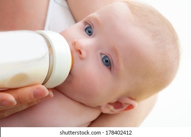 Bond Little Baby With Blue Eyes Drinking Bottle Milk In Mother Arms