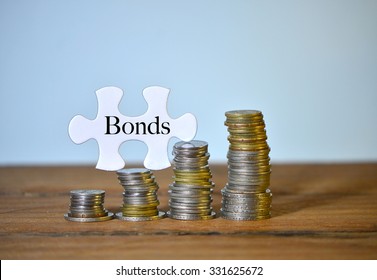 Bonds Text Written On Puzzle With Stacked Coins On Wood Table.