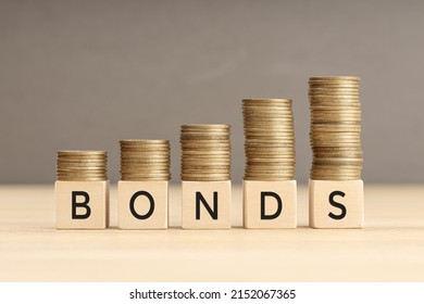 Bonds word in wooden blocks with coins stacked in increasing stacks. Bonds increasing concept. Copy space - Shutterstock ID 2152067365