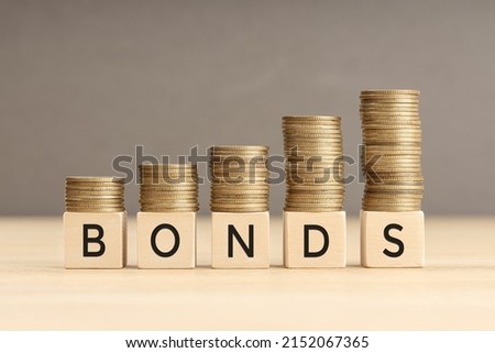 Bonds word in wooden blocks with coins stacked in increasing stacks. Bonds increasing concept. Copy space