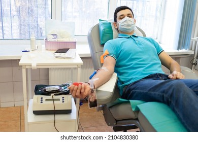 Bone Marrow Donation. Man In Medical Mask, Male Hand Holding Red Ball, Blood Transfusion System, Blood Bag. Soft Focus