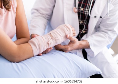 Bone specialist doctor examining serious injured woman at her arm with splint and bandage. Physician doctor talking to broken arm woman patient in the hospital. Healing in injured person concept. - Powered by Shutterstock