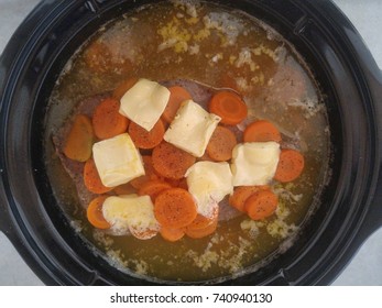 Boneless Bottom Round Roast In Crock Pot With Potatoes Carrots Seasoning And Melting Butter