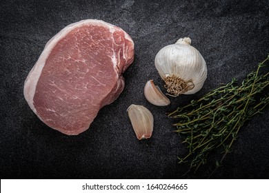 Boneless Center Cut Pork Chop With Thyme And Garlic On A Slate Background