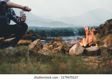 Bonfire In Camping Of People Camper Group In Nature Near The Mountains With Coffee Brewing Equipment.