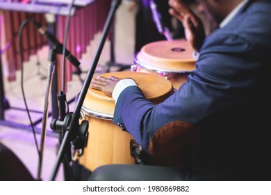 Bongo drummer percussionist performing on a stage with conga drums set kit during jazz rock show performance, with latin cuban band performing in the background, drummer point of view 