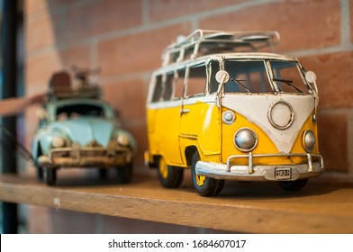 BONIFACIO GLOBAL CITY, PHILIPPINES - MARCH 3, 2018: A yellow toy van that resembles a Volkswagen Kombi with another toy car blurred behind it that resembles a Beetle.
