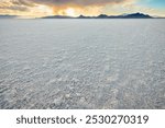 Bonneville Salt Flats low angle view with blue yellow colorful landscape sunset by Salt Lake City, Utah with mountains and dramatic sun with clouds