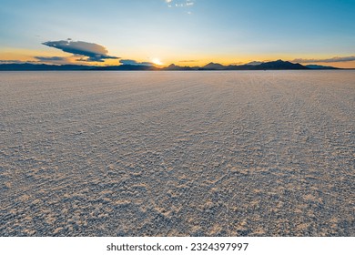 Bonneville Salt Flats low angle view with blue yellow colorful landscape sunset near Salt Lake City, Utah and silhouette view of mountains and sun setting behind clouds - Powered by Shutterstock