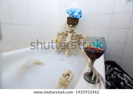 Bony skeleton taking a bubble bath in a grungy off-white dirty tub