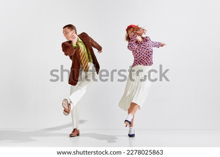 Boogie-woogie. Young man and woman in stylish clothes dancing retro dance against grey studio background. Concept of art, retro style, hobby, party, fun, movements, 60s, 70s culture