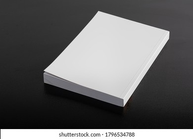 Book with blank cover on dark glossy table, editable mock-up series ready for your design, cover selection path included. 
