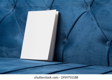 Book with blank cover on velvet blue sofa, editable PSD mock-up series with smart object layers ready for your design, book cover selection path included.